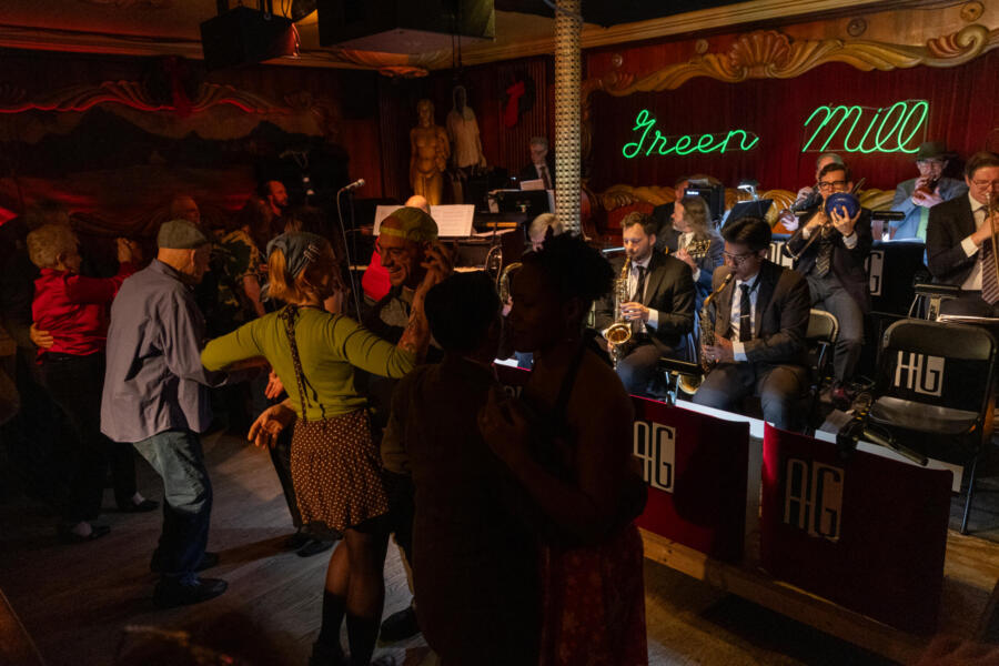 Patrons dance on dance floor as musicians play instruments on stage at the The Green Mill in Uptown.