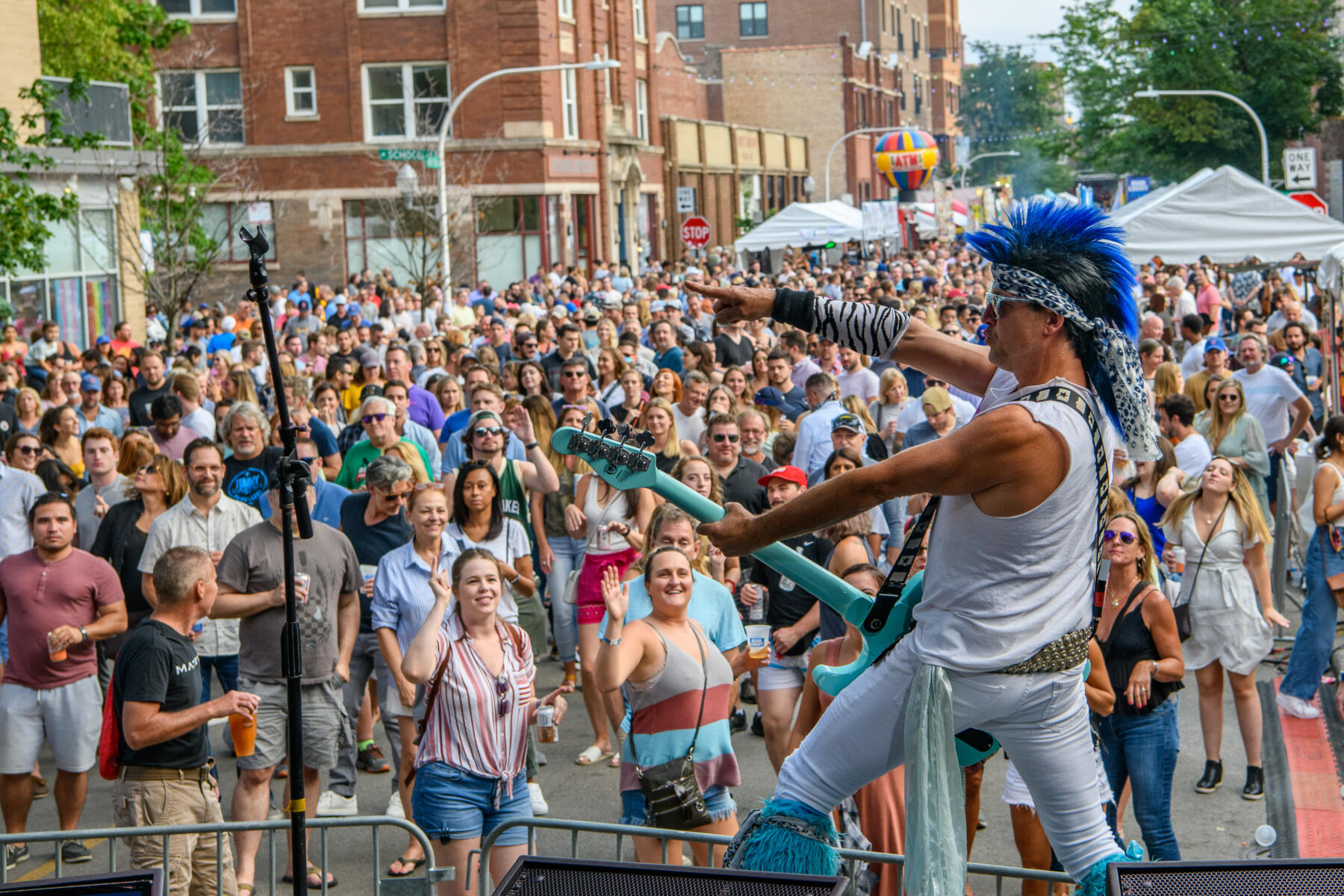 Huge crowd of Chicagoans enjoy live music as musician plays guitar on stage.