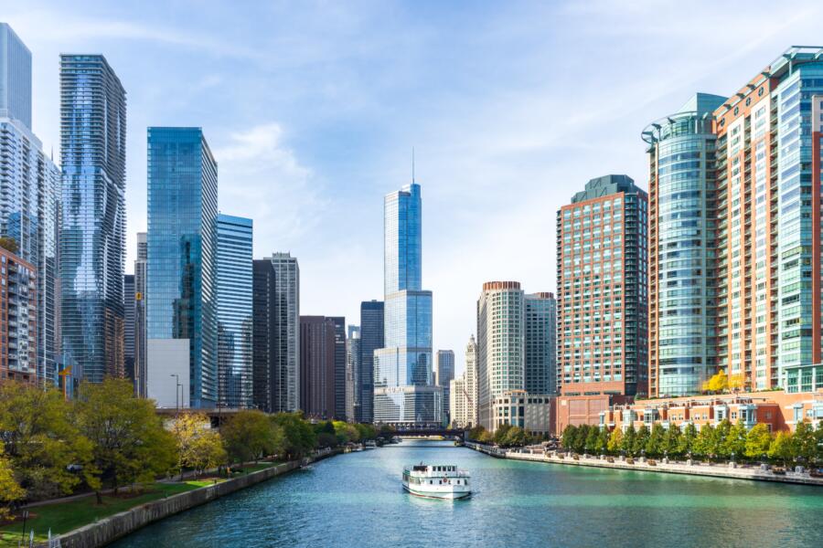 A boat drifts down the Chicago River with the scenic skyline in the background.