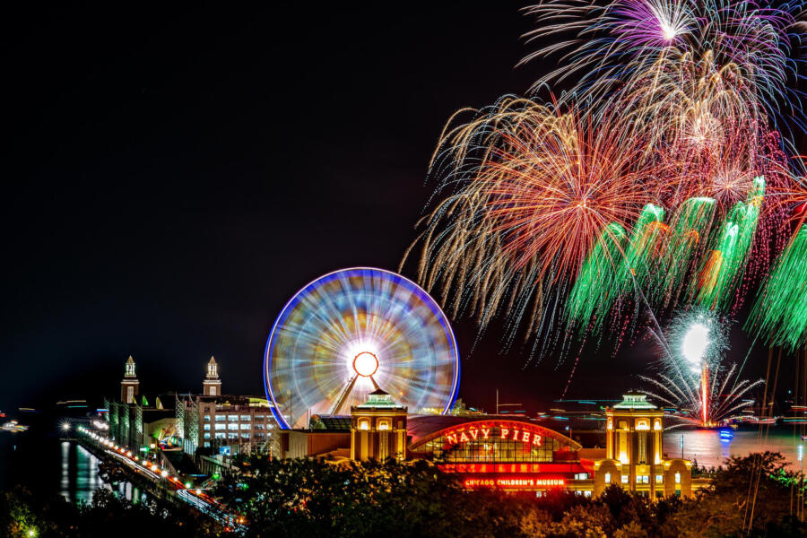 Colorful fireworks explode at Navy Pier above the ferris wheel as colors fill the sky
