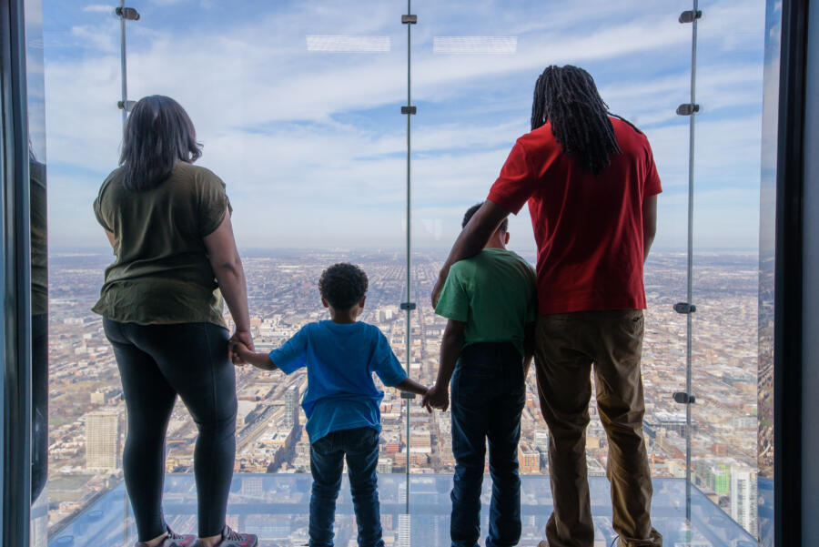 A family of four stands above the scenic view of Chicago at the Skydeck.
